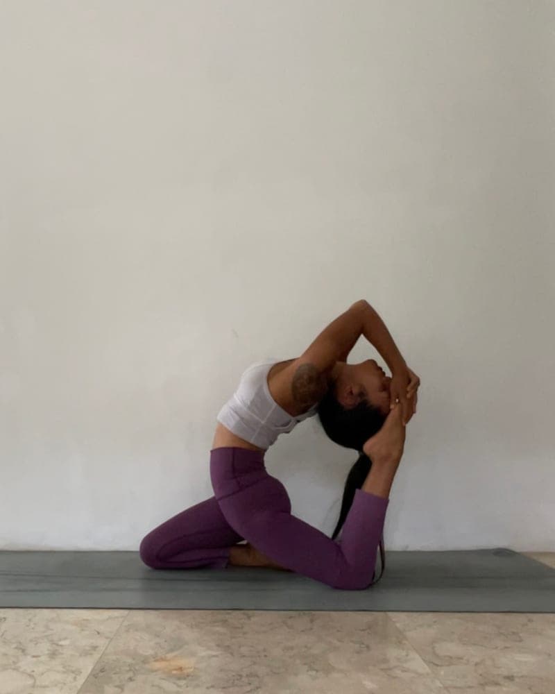 Nicha in a seated backbend, soft mauve and ivory tones