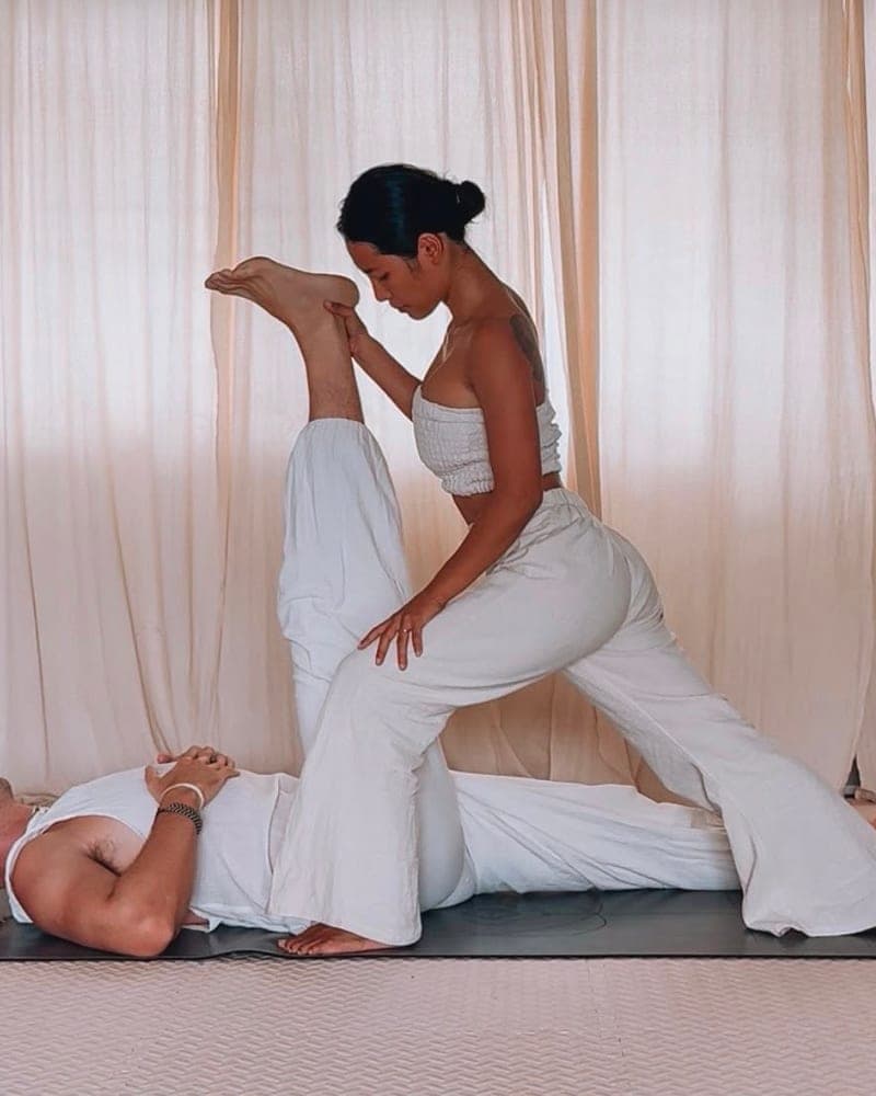Nicha leaning into an assisted hamstring stretch during a Thai Yoga Massage session